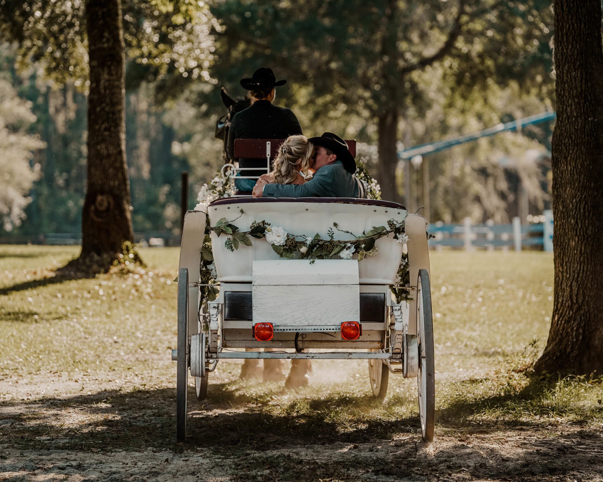 Photo of bride and groom exiting the ceremony via horse and carriage.