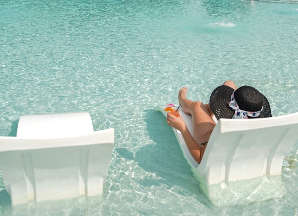 Guests relaxing and swimming under the sun in the outdoor resort pool surrounded by trees