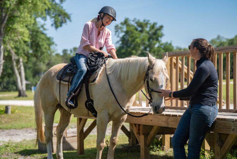 Black Prong trail guide helping a guest on a horse